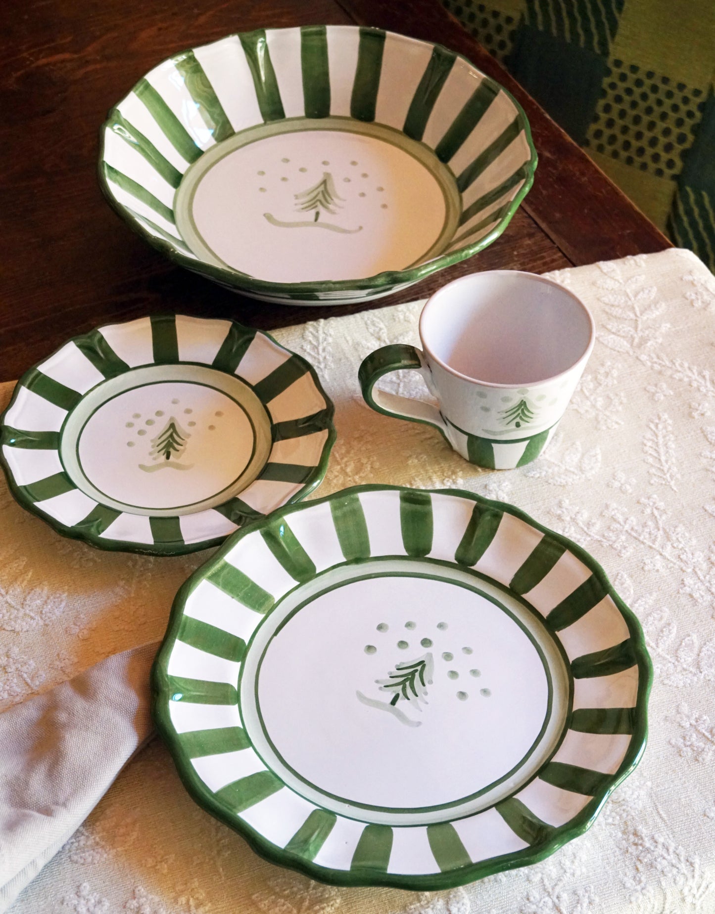 Set of ceramic plates and a mug with green and white striped designs on a wooden surface.