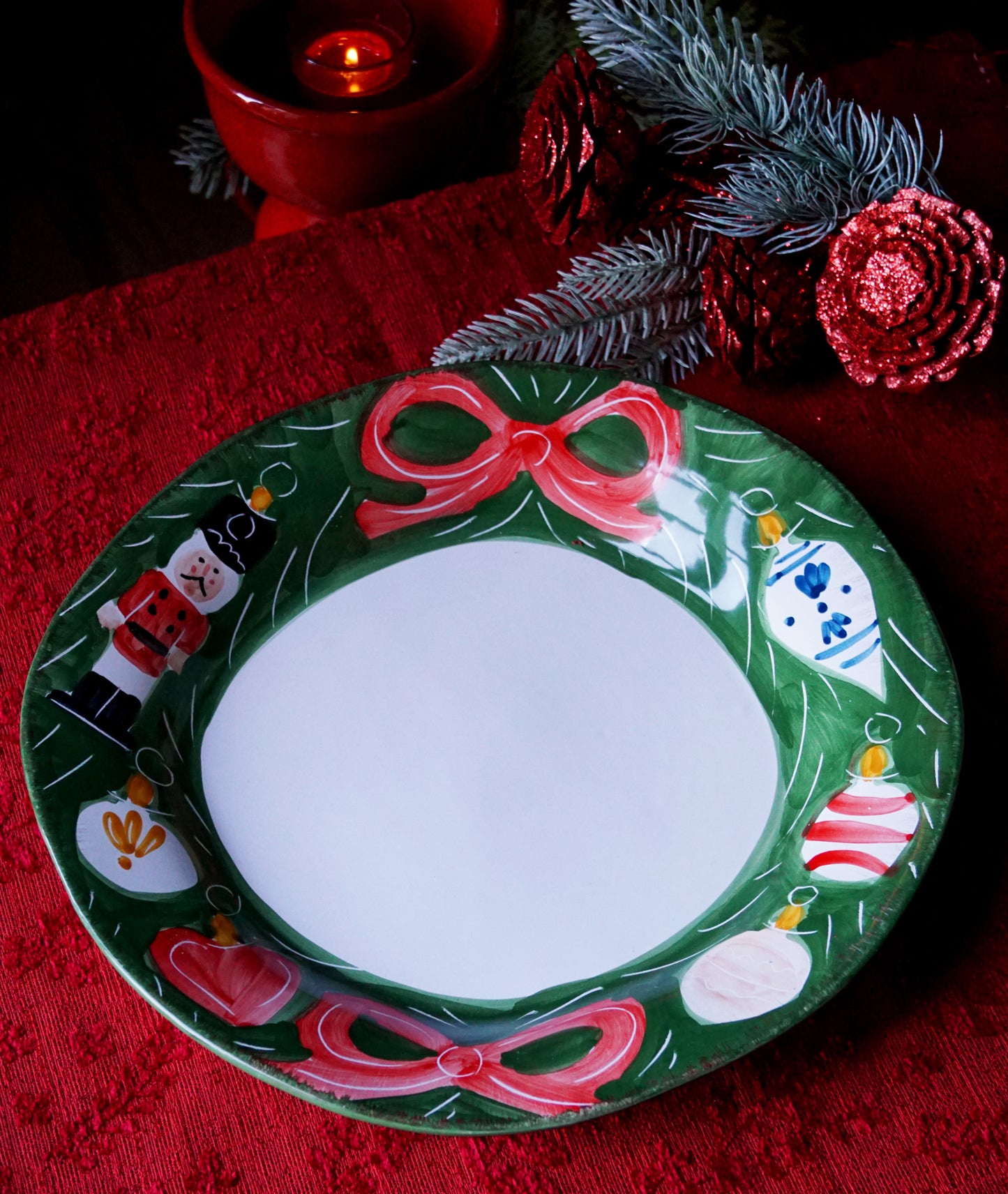 Decorative Christmas serving plate with ornaments and red bows on a green surface.