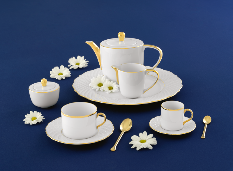 White porcelain tea set with gold accents on a blue background