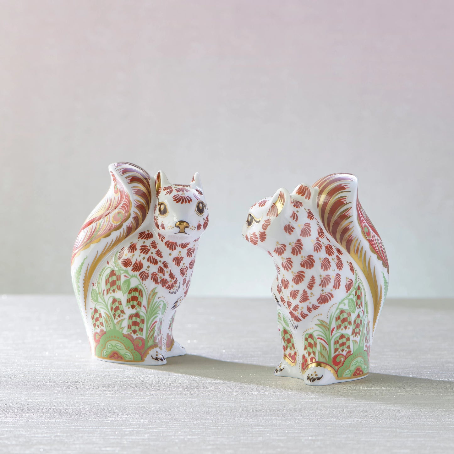 Two decorative squirrel figurines with floral patterns on a light background