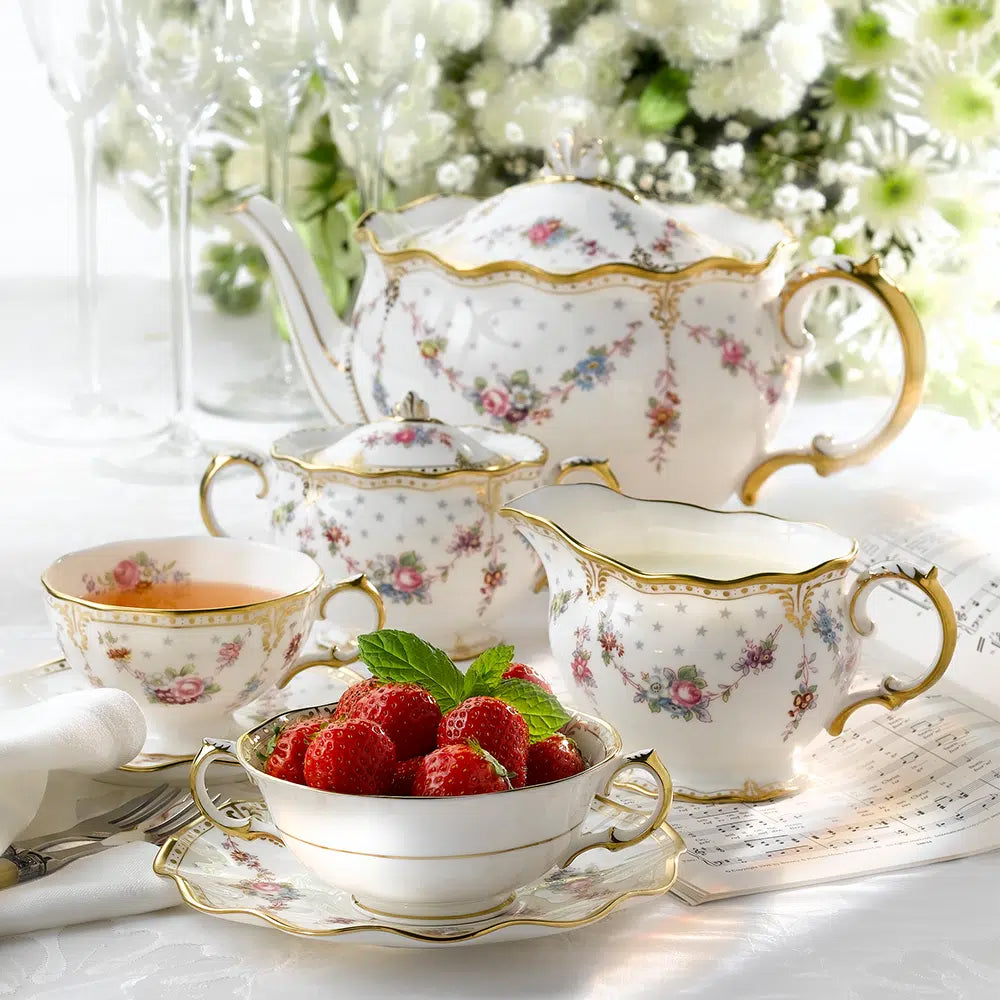 Tea set with floral patterns on a table with raspberries