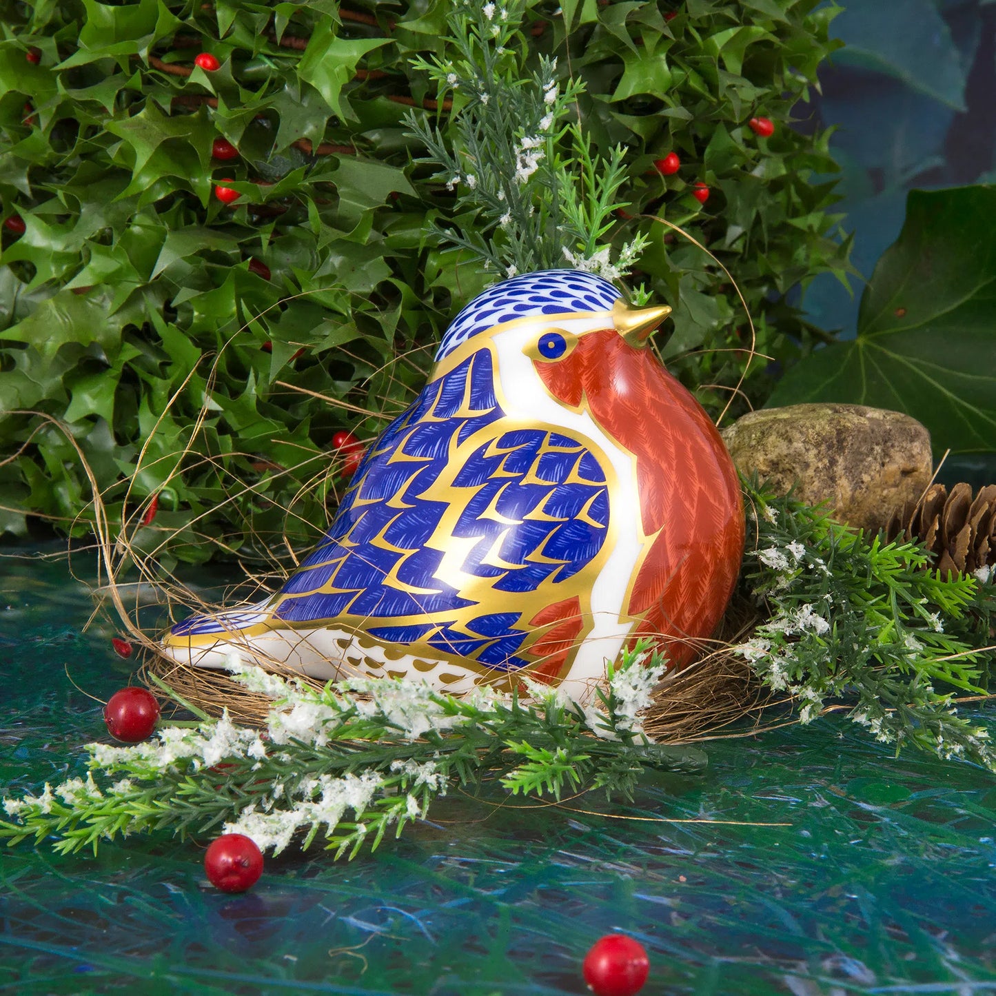 Decorative robin bone china figurine with blue and red pattern on a green background
