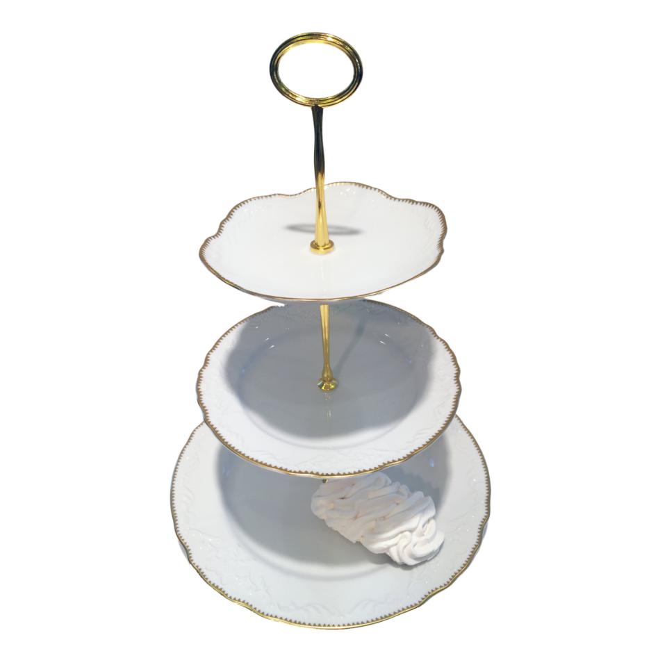 A three-tiered white porcelain serving tray with gold banding and a circular handle on top.