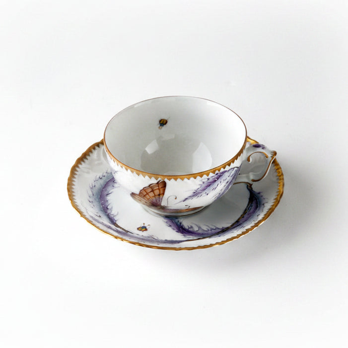 A tea cup & saucer featuring a thistle design with floral patterns and gold accents on the edges.