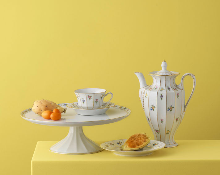 Tea set with teapot, cups, and cake stand on a yellow background