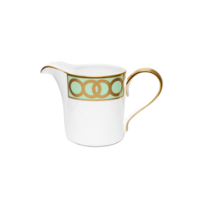 White creamer with gold and green design on a white background