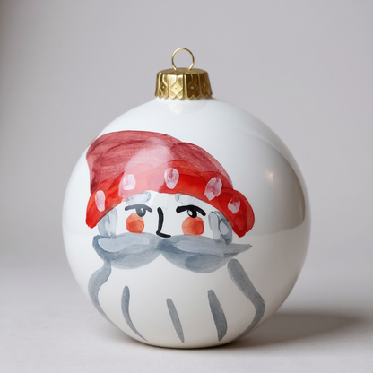 Decorative Christmas ornament with a painted Santa and red hat on a plain background