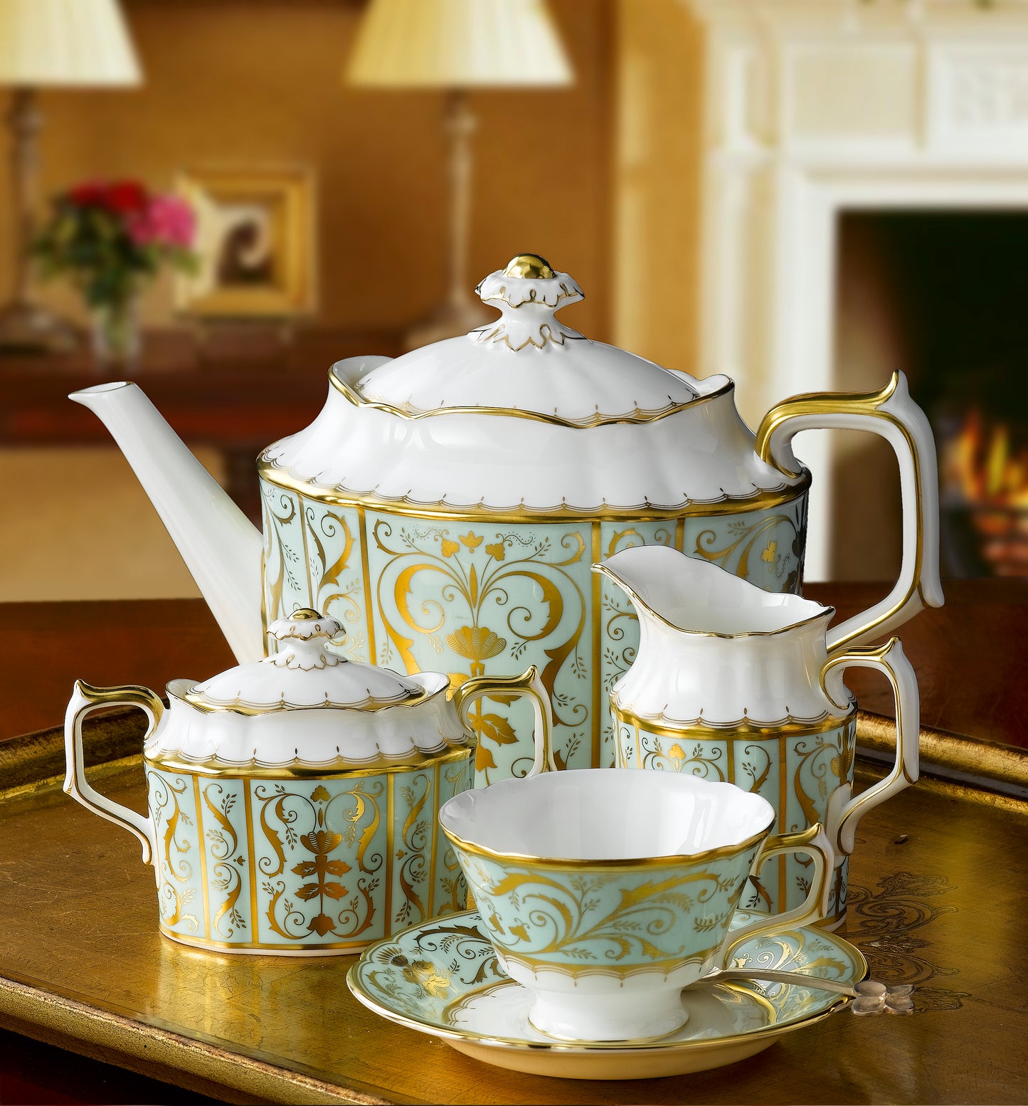 Luxury tea set hand made in England with gold and white patterns on a wooden table.