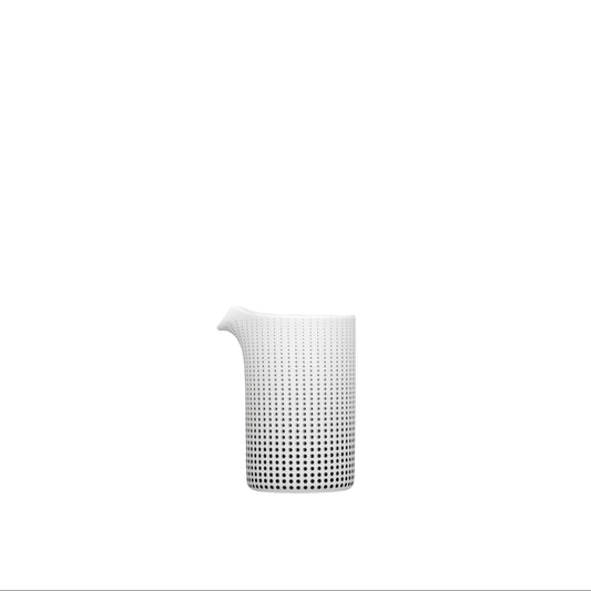 A white porcelain creamer with black and gold geometric patterns on it, with a modern design.