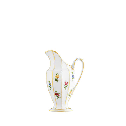 A white porcelain creamer with floral patterns and gold accents.