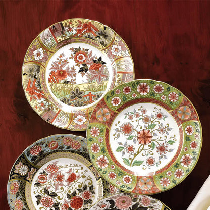 Set of decorative plates with floral and nature-themed designs on a wood table