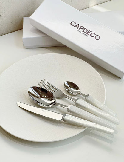 Silver cutlery set on a white plate with a 'Capdeo' branded box in the background.