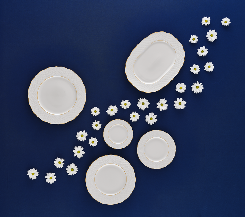 White porcelain plates on a blue background with daisies