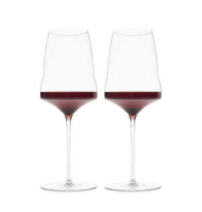 Two premium hand-blown wine glasses filled with red wine on a white background