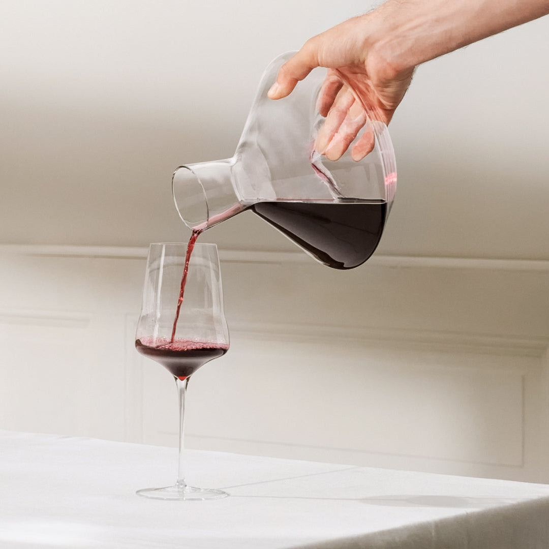 Hand blown wine glass being filled with red wine from a luxury decanter