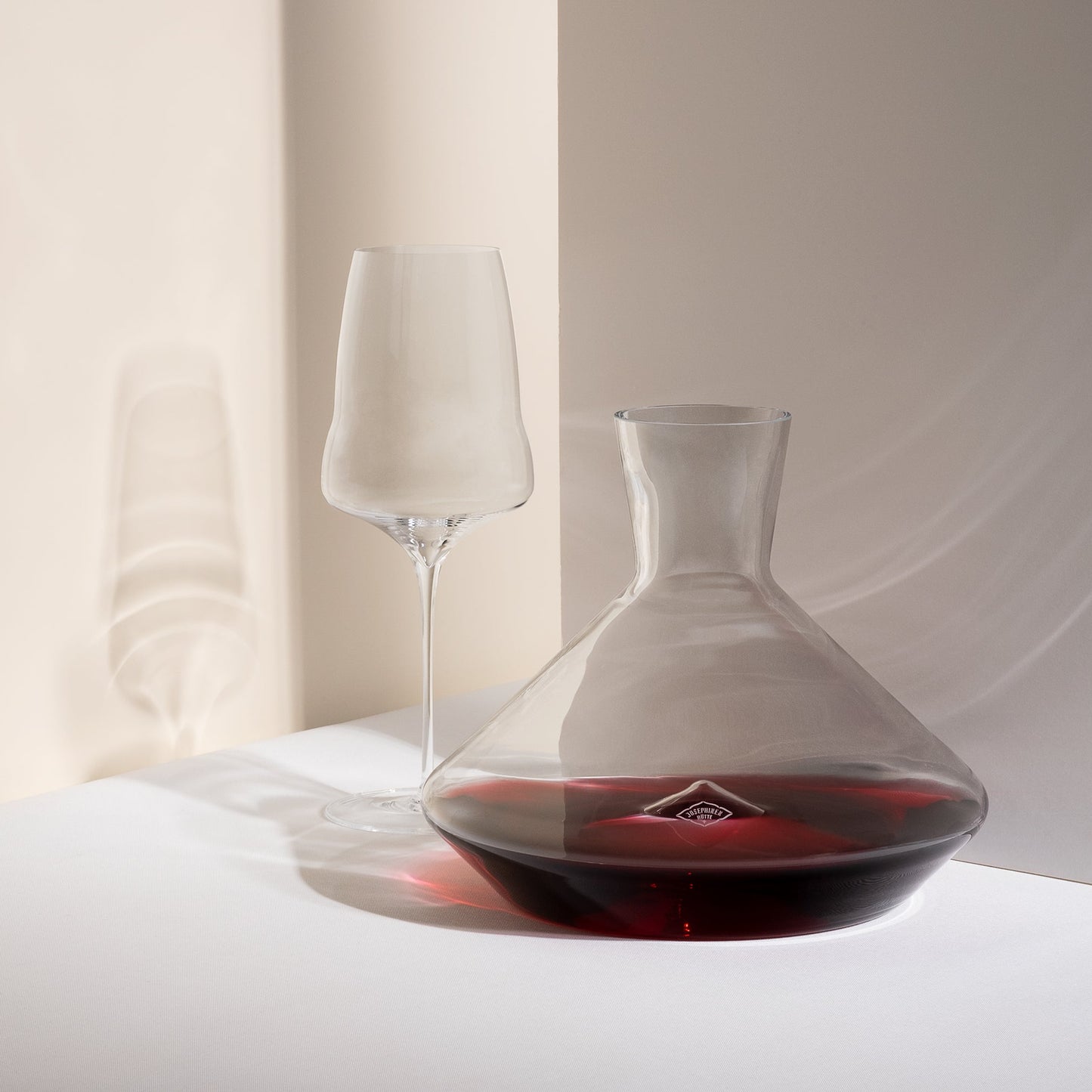 Hand blown wine glass sitting next to a luxury decanter filled with red wine