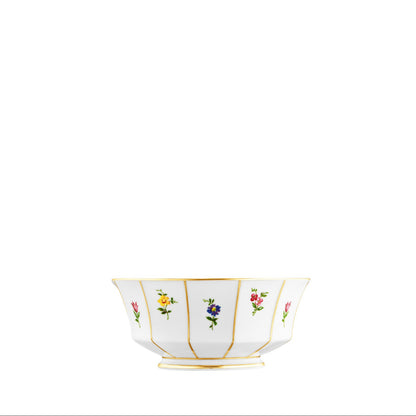 A white porcelain bowl with gold trim and small floral decorations arranged in a pattern around the edge.