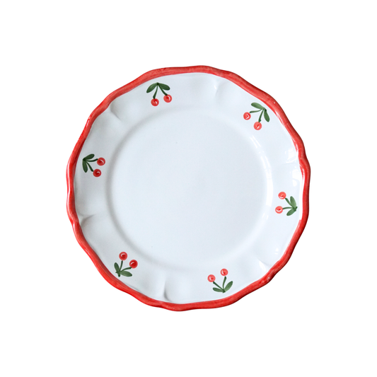 White plate with red rim and cherry design on a white background