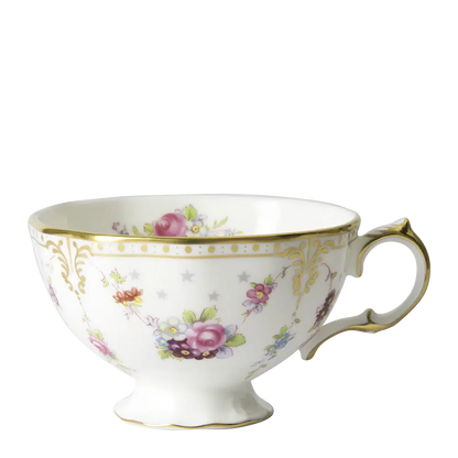 A white fine bone china tea cup with a scalloped gold border and floral patterns, including stars.