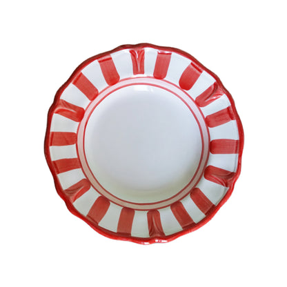 White hand-made ceramic plate with red striped rim on a white background