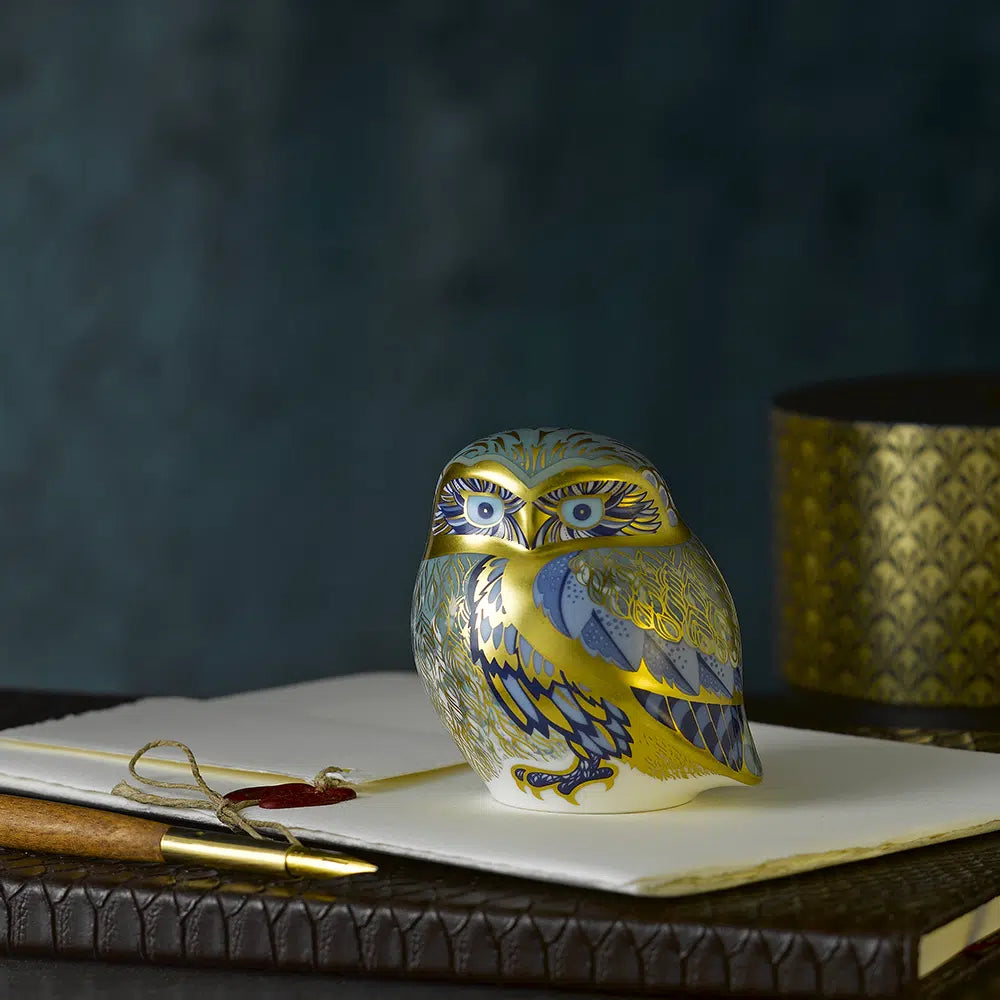 Decorative bone china owl figurine on a surface with a dark background