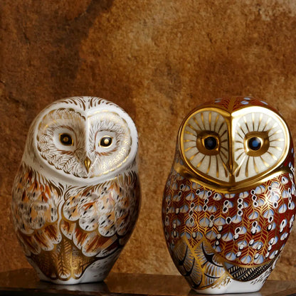 Two ornate owl bone china figurines on a brown background