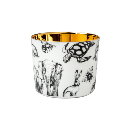 A white porcelain champagne tumbler with a gold interior, decorated with different animals in partnership with Barbara Strum