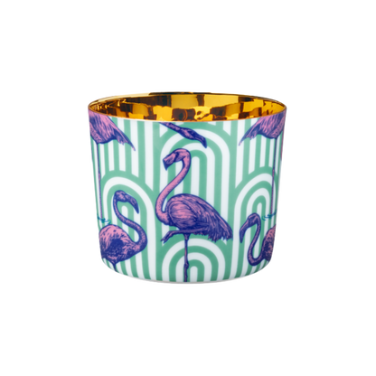 A multicolored porcelain champagne tumbler with a gold interior, decorated with pink flamingo patterns against a teal background.