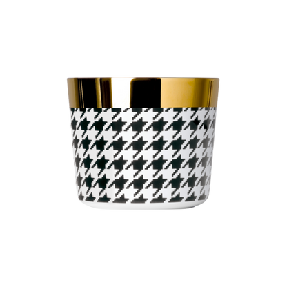 A black and white porcelain champagne tumbler with a gold rim and interior, featuring a geometric pattern.