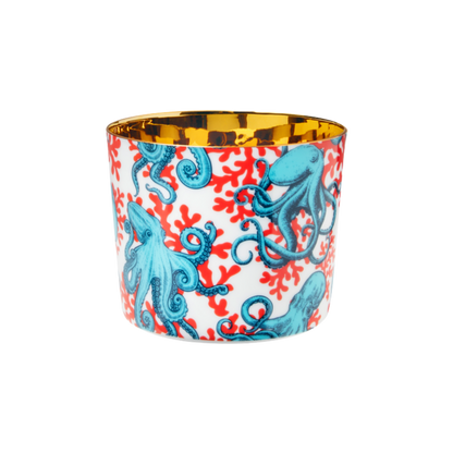 A multicolored porcelain champagne tumbler with a gold interior, decorated with blue octopus against a red and white patterned background.