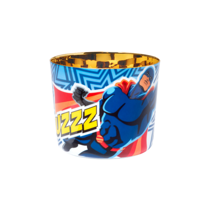 A porcelain champagne tumbler with a colorful illustration featuring Superman and the text 'BUZZZZZ' on a blue background, with a golden interior.