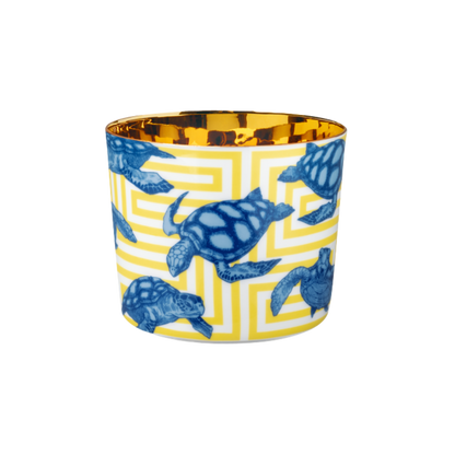 A multicolored porcelain champagne tumbler with a gold interior, decorated with blue turtle patterns against a yellow background.