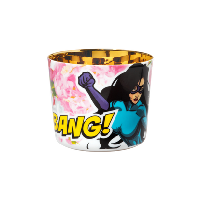 A porcelain champagne tumbler with a colorful illustration featuring a woman superhero and the text 'BANG!' on a pink rose background, with a golden interior.