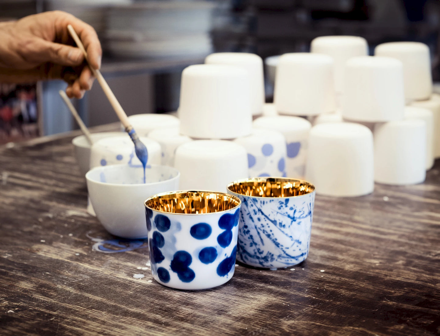 Decorative luxury ceramic cups with blue hand painted design on a wooden surface.
