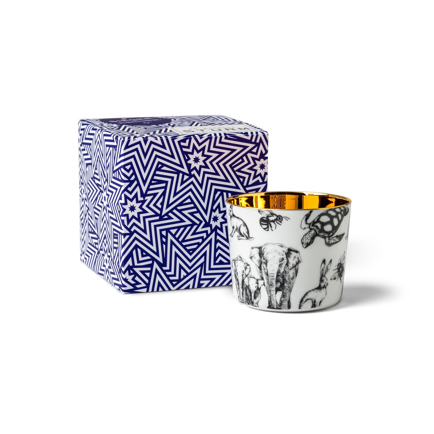 Porcelain champagne tumbler with animal design sitting next to a patterned gift box on a white background