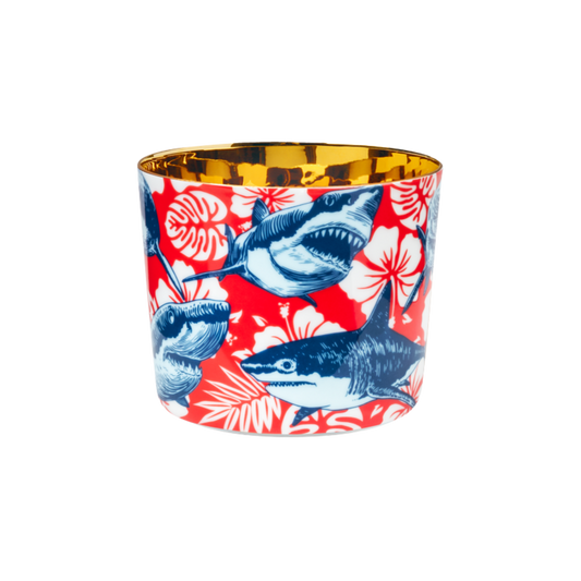 A multicolored porcelain champagne tumbler with a gold interior, decorated with blue sharks against a red patterned background.